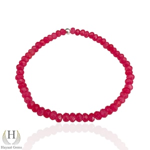 May include: A vibrant red gemstone bracelet. The bracelet is composed of numerous small, faceted, round gemstones strung together. The gemstones are a deep, rich red color. The bracelet is displayed against a white background.