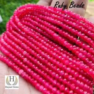 Puede incluir: Una hebra de cuentas de rubí rosa brillante. Las cuentas son facetadas y tienen un acabado brillante. Las cuentas están enhebradas en un hilo transparente. La imagen incluye el texto "Ruby Beads".