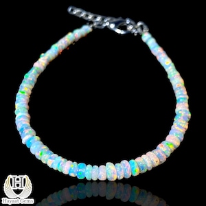 May include: A beaded bracelet featuring small, round, translucent opal beads with iridescent flashes of blue, green, and orange. The bracelet includes a silver-toned metal lobster clasp and an adjustable chain link extension.