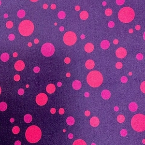 May include: A purple fabric with a repeating pattern of pink polka dots of varying sizes.