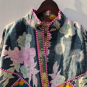Puede incluir: Chaqueta acolchada con estampado floral en tonos azules, rosas y amarillos. La chaqueta tiene cuello alto y ribete rosa. El dise&ntilde;o incluye parches de diferentes telas florales.