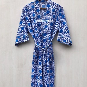 May include: A white cotton robe with a blue floral print and a matching tie belt. The robe has a collar and three-quarter sleeves.