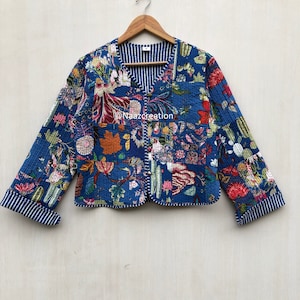 Może przedstawiać: Niebieska pikowana kurtka z kwiatowym nadrukiem i podszewką w paski. Kurtka ma dekolt w kształcie litery V i 3/4 rękawy.