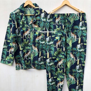 Puede incluir: Un conjunto de pijama azul con estampado de guepardo verde y marrón. El conjunto incluye una camisa de manga larga con cuello abotonado y pantalones a juego.