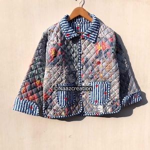 May include: A quilted jacket featuring a grey floral pattern with blue and white striped accents on the collar, cuffs, and pockets. The garment includes small red heart details, a button-front closure, and the text Naazcreation on the front.