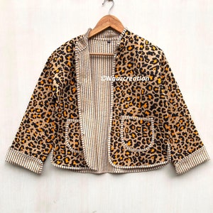 Puede incluir: Una chaqueta acolchada de estampado de leopardo marrón y naranja con forro a rayas y dos bolsillos. La chaqueta tiene un cuello mandarín y cierre de botón.