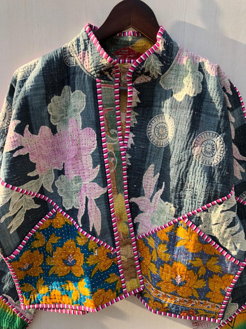 Puede incluir: Chaqueta acolchada con estampado floral en tonos azules, rosas y amarillos. La chaqueta tiene cuello alto y ribete rosa. El dise&ntilde;o incluye parches de diferentes telas florales.