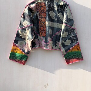Puede incluir: Chaqueta patchwork con cuello alzado, con estampados florales y geom&eacute;tricos en azul marino, naranja y crema. La chaqueta tiene un dise&ntilde;o corto con detalles arco&iacute;ris en las mangas y est&aacute; ribeteada con costuras rosas.