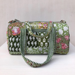 May include: A quilted duffel bag featuring a patchwork design in shades of green, white, and pink with floral and paisley patterns. The bag includes two striped handles, a zippered front pocket, and the text Naazcreation printed on the front.