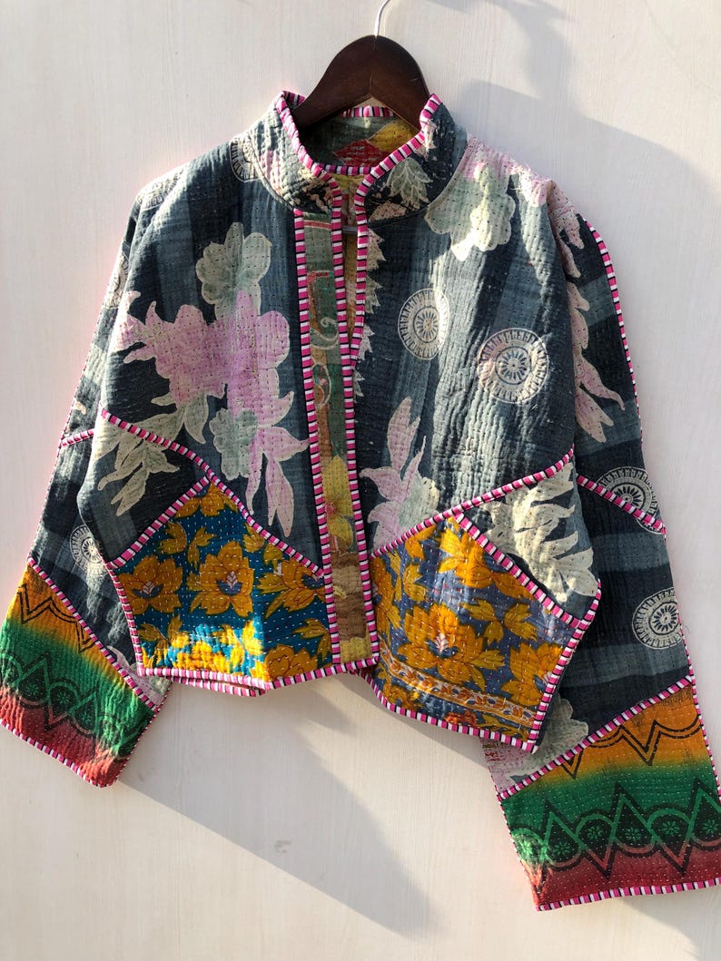 Puede incluir: Chaqueta patchwork con cuello alzado, con estampados florales y geom&eacute;tricos en tonos azul, amarillo, rosa y verde. La chaqueta tiene una textura acolchada y est&aacute; ribeteada con costuras rosas.