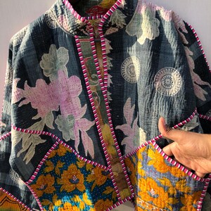 Puede incluir: Chaqueta patchwork con base azul oscuro, con estampados florales en rosa, amarillo y blanco. Tiene cuello mandar&iacute;n y ribetes rosas. El dise&ntilde;o incluye varios parches de tela con diferentes patrones florales y geom&eacute;tricos.