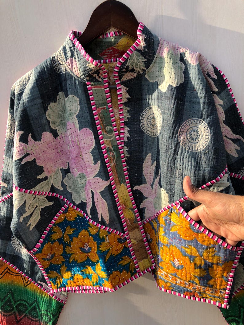 Puede incluir: Chaqueta patchwork con base azul oscuro, con estampados florales en rosa, amarillo y blanco. Tiene cuello mandar&iacute;n y ribetes rosas. El dise&ntilde;o incluye varios parches de tela con diferentes patrones florales y geom&eacute;tricos.
