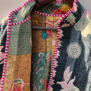 Puede incluir: Chaqueta acolchada con dise&ntilde;o patchwork. La chaqueta presenta una mezcla de estampados florales y geom&eacute;tricos en tonos azules, verdes, amarillos y rosas. Los bordes est&aacute;n ribeteados con un borde a rayas rosa y blanco.