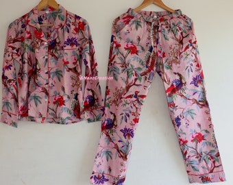 May include: A pink pajama set with a floral print featuring birds and flowers. The top has a button-up front and long sleeves. The pants have an elastic waistband and a drawstring.