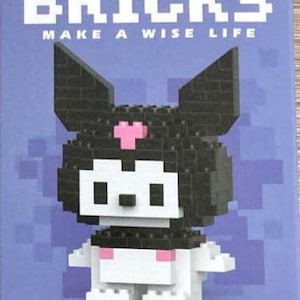 May include: A black and white brick building kit of a cartoon character with a pink heart on its chest. The box says "BRICKS MAKE A WISE LIFE" and "W2601-16 151PCS 14+ AGES".