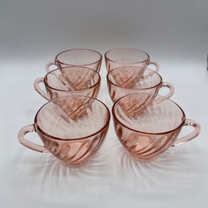 May include: Set of six pink glass teacups with a swirl design. The cups are perfect for a vintage tea party.