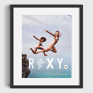 May include: Two women jump off a cliff into the ocean. The text "Let the sea set you free" and the word "RXY" are written in white on a rock face. The RXY logo is a small white circle with a blue dot in the center.