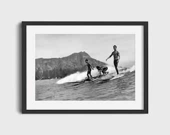 May include: Three people surfing on longboards in the ocean with a mountain in the background.