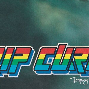 May include: A colorful logo for Rip Curl Wetsuits, featuring the brand name in a rainbow color scheme with a 3D effect. The logo is set against a dark green background with the text "Torquay, Australia." below it.