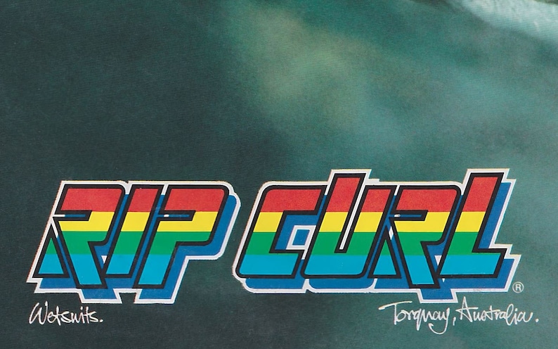 May include: A colorful logo for Rip Curl Wetsuits, featuring the brand name in a rainbow color scheme with a 3D effect. The logo is set against a dark green background with the text "Torquay, Australia." below it.
