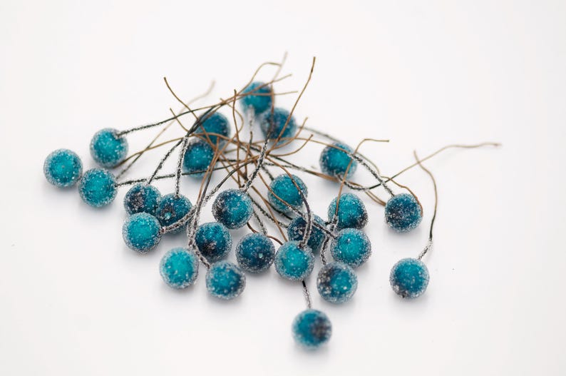May include: A cluster of teal blue berry-shaped ornaments with a frosted finish, attached to thin brown wire stems.
