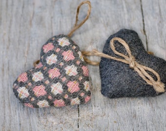 Puede incluir: Dos corazones de tela, uno gris y otro con un patrón geométrico rosa y blanco, están atados con un cordel.