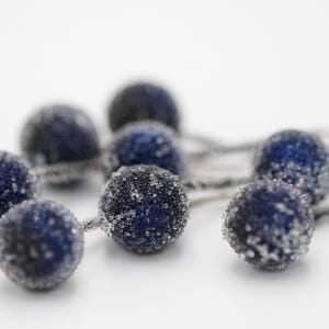 May include: A string of blue and silver decorative balls with a frosted finish. The balls are connected by silver wire.