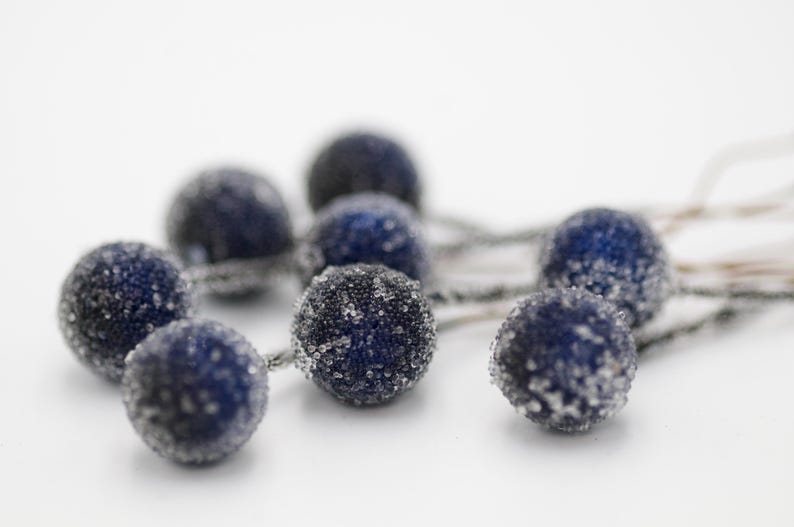 May include: A string of blue and silver decorative balls with a frosted finish. The balls are connected by silver wire.