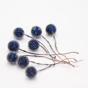 May include: A cluster of blue frosted berry sprigs with brown wire stems.