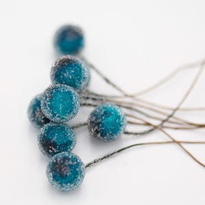 May include: A cluster of blue and silver frosted berry-shaped ornaments with thin wire stems.