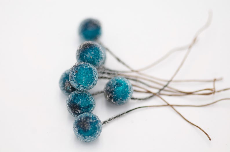 May include: A cluster of blue and silver frosted berry-shaped ornaments with thin wire stems.