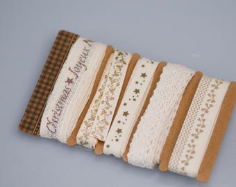 May include: A set of six white and cream colored ribbon spools with different patterns. The ribbons have gold and brown printed designs, including stars, dots, and the words "Christmas Joy".