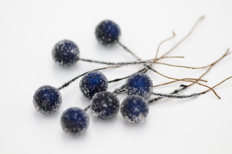 May include: A cluster of seven blue berry-shaped ornaments with a frosted finish, each attached to a thin brown twig.