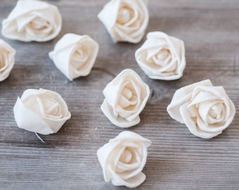May include: Nine white fabric roses arranged on a wooden surface. The roses are made of a soft, textured fabric and have a realistic appearance.