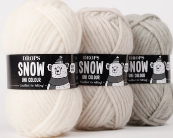 May include: Three skeins of yarn in white, light gray, and gray. Each skein has a label that reads "DROPS SNOW UNI COLOUR - Excellent for knitting."