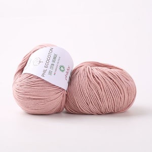 May include: Two balls of pale pink yarn, one with a white label that reads "PHIL ECOCOTON 100% COTTON ORGANIQUE FABRIQUE EN ITALIE" and a green logo that says "phil&tor".