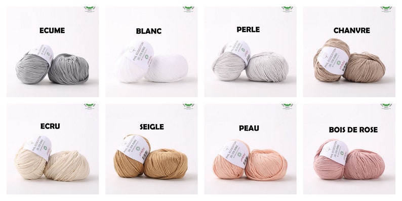 May include: Eight balls of yarn in different colors, including white, gray, beige, brown, and pink. Each ball has a label with the name of the color in French.