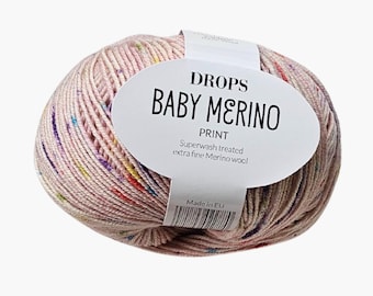 May include: A ball of light pink yarn with multicolored speckles, wrapped in a white paper label that reads DROPS BABY MERINO PRINT, Superwash treated extra fine Merino wool, and Made in EU, featuring a barcode at the bottom center.