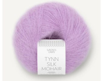 May include: A ball of light purple Tynn Silk Mohair yarn. The yarn is fluffy and soft, with a label that reads "Sandnes Garn" and "Tynn Silk Mohair". The yarn is a pastel color, perfect for knitting or crocheting projects.