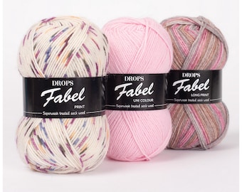 May include: Three skeins of Drops Fabel yarn. The skein on the left is a multi-colored print with white, brown, pink, and blue. The middle skein is a solid pink. The skein on the right is a long print with pink, brown, and white.