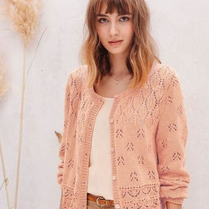 May include: A light pink knitted cardigan with a delicate lace pattern. The cardigan has a button-up front and long sleeves.