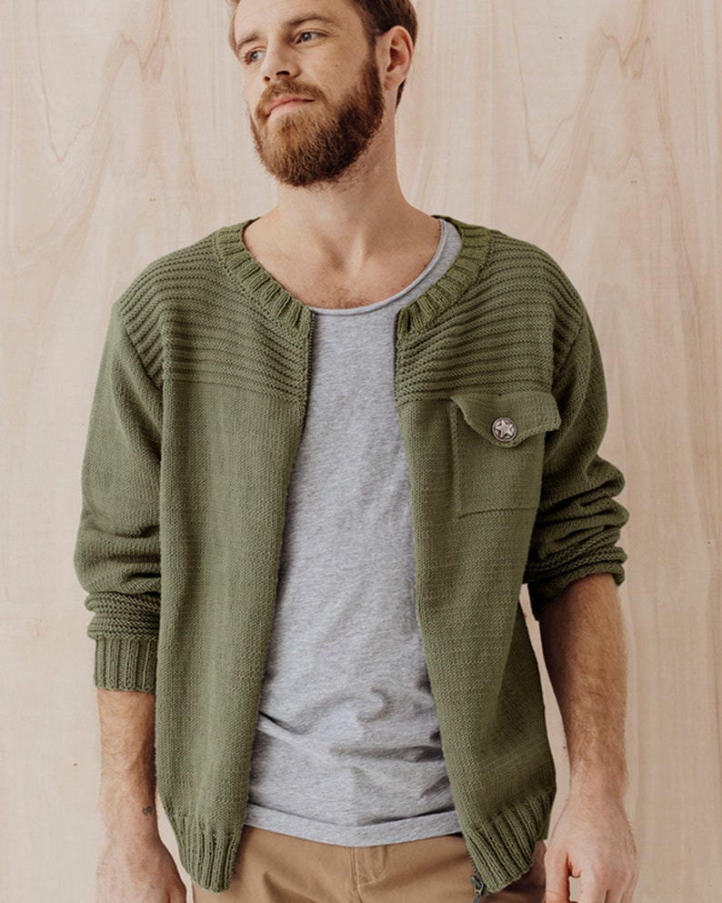 May include: A green knitted cardigan with a buttoned pocket on the left side. The cardigan has a ribbed collar and cuffs.