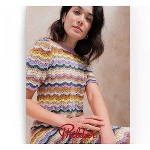May include: A woman in a colourful, short-sleeved crochet top and skirt with a wave pattern. The top has a purple neckline and the skirt is visible at the bottom. The word "Phildar" is printed in red script at the bottom.