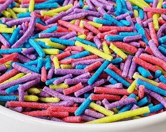 Könnte beinhalten: Eine Schüssel gefüllt mit bunten Streuseln. Die Streusel sind in den Farben Rosa, Lila, Gelb und Blau.