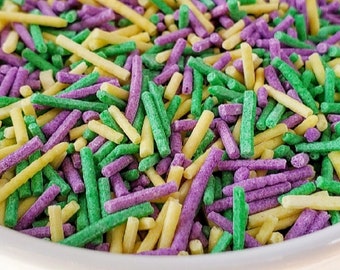 Puede incluir: Un bol blanco lleno de sprinkles amarillos, verdes y morados. Los sprinkles son largos y delgados, y son perfectos para decorar pasteles y cupcakes.