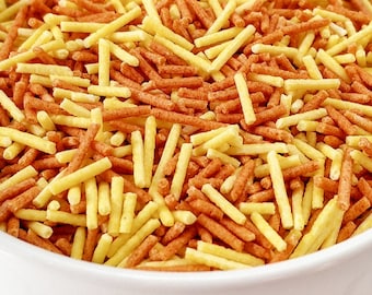 Könnte beinhalten: Eine weiße Schüssel gefüllt mit orangefarbenen und gelben Streuseln. Die Streusel sind lang und dünn und ähneln gekochten Nudeln.