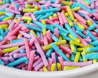 Könnte beinhalten: Eine weiße Schüssel gefüllt mit bunten Streuseln. Die Streusel sind lang und dünn und in den Farben Rosa, Blau, Gelb und Grün.