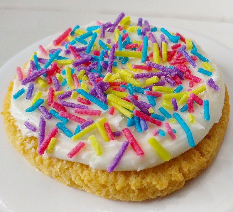 Puede incluir: Una galleta redonda de az&uacute;car cubierta con glaseado blanco y espolvoreada con coloridos sprinkles.