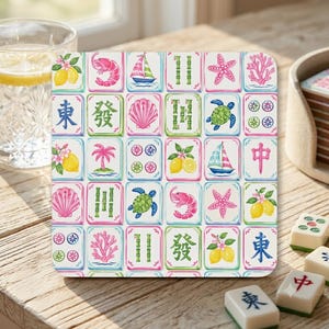 May include: A square coaster featuring a grid of colorful illustrations including pink shrimp, sailboats, green bamboo stalks, pink starfish, coral, sea turtles, seashells, lemons with blossoms, and blue Chinese characters on a white background.