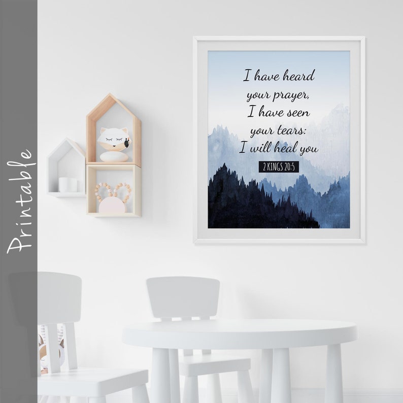 Op de afbeelding: Een printbare wandkunstprint met een aquarel achtergrond van blauwe en grijze bergen. De print heeft een wit frame en de tekst "Ik heb je gebed gehoord, ik heb je tranen gezien: Ik zal je genezen 2 KONINGEN 20:5".